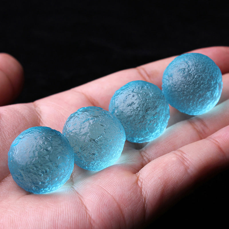 Blue glass marbles held in a hand against a dark background
