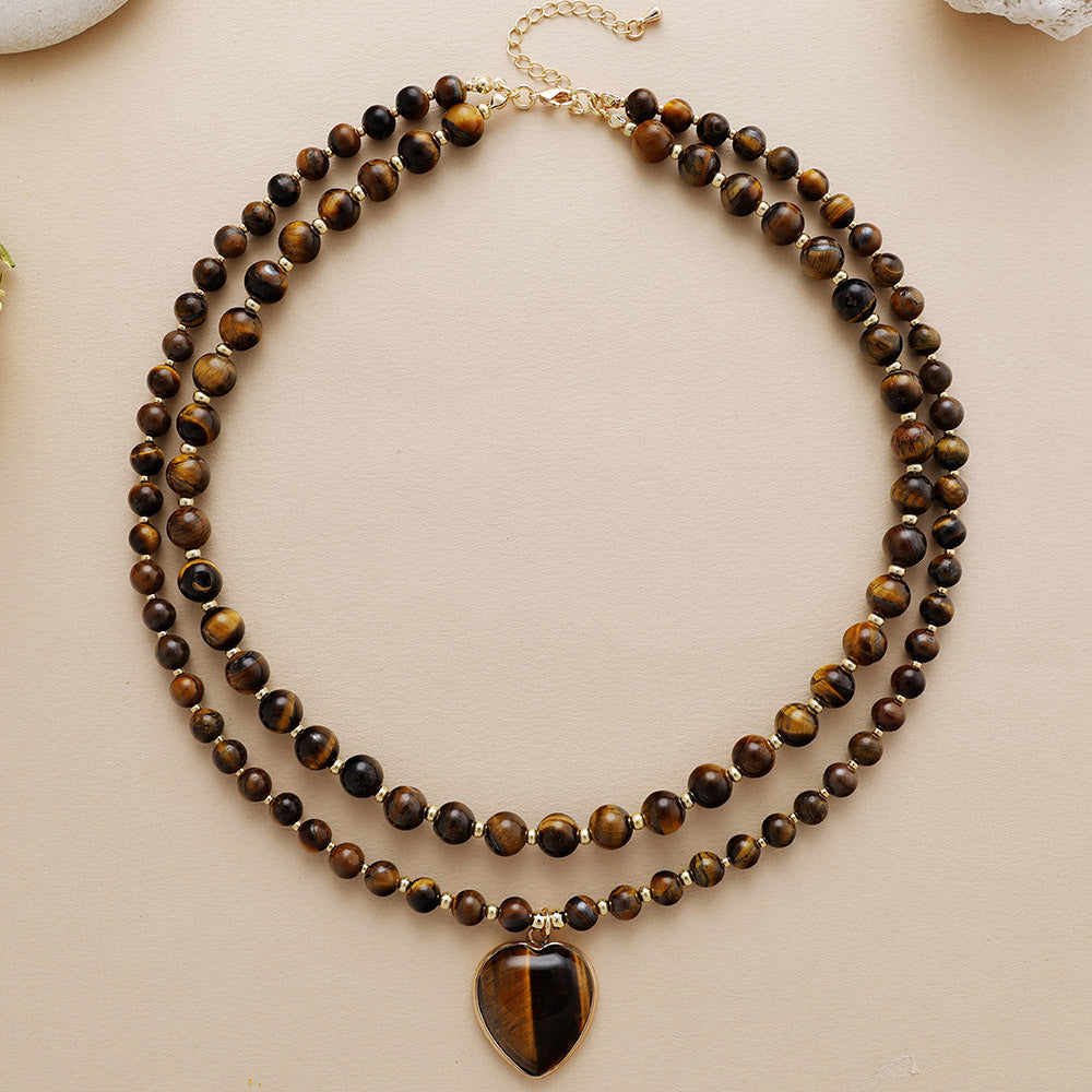 Double-layered beaded necklace with a heart-shaped pendant on a beige background