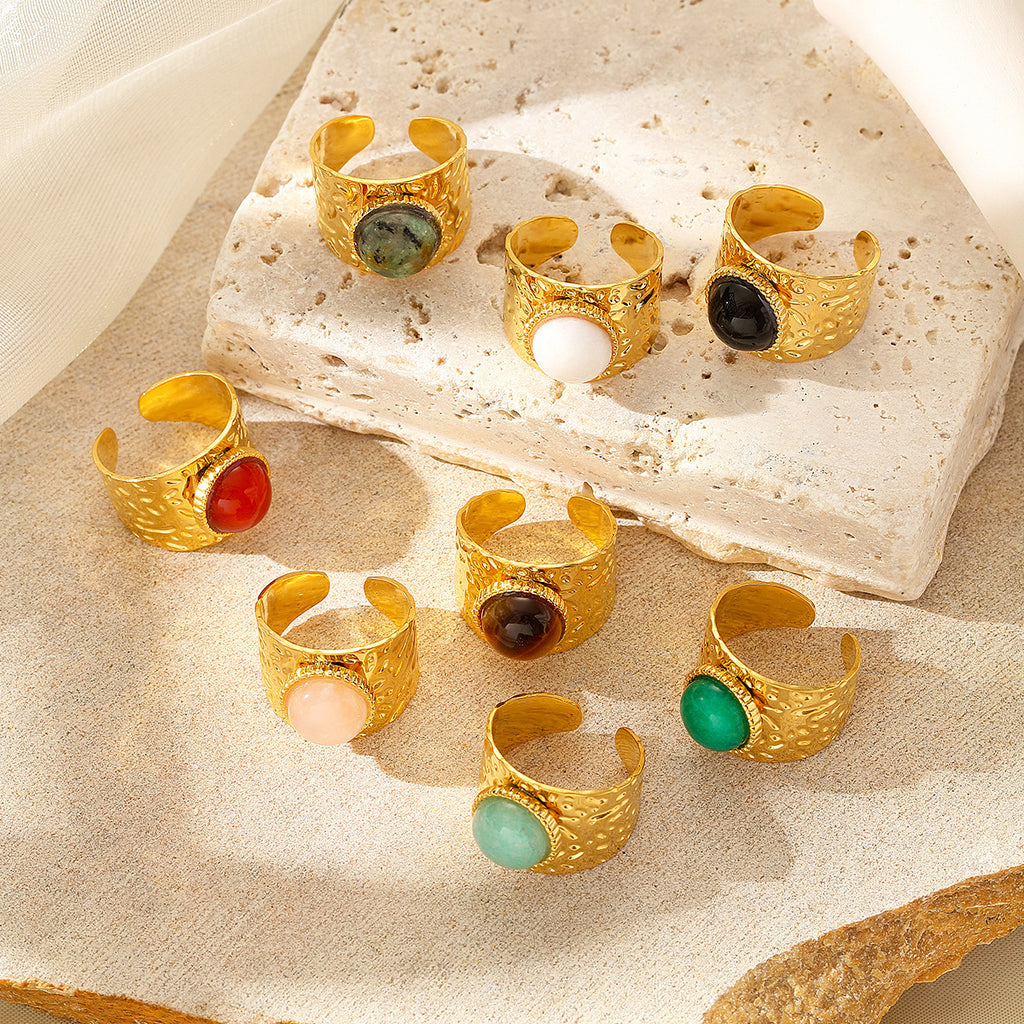Gold rings with colorful gemstones on a textured surface