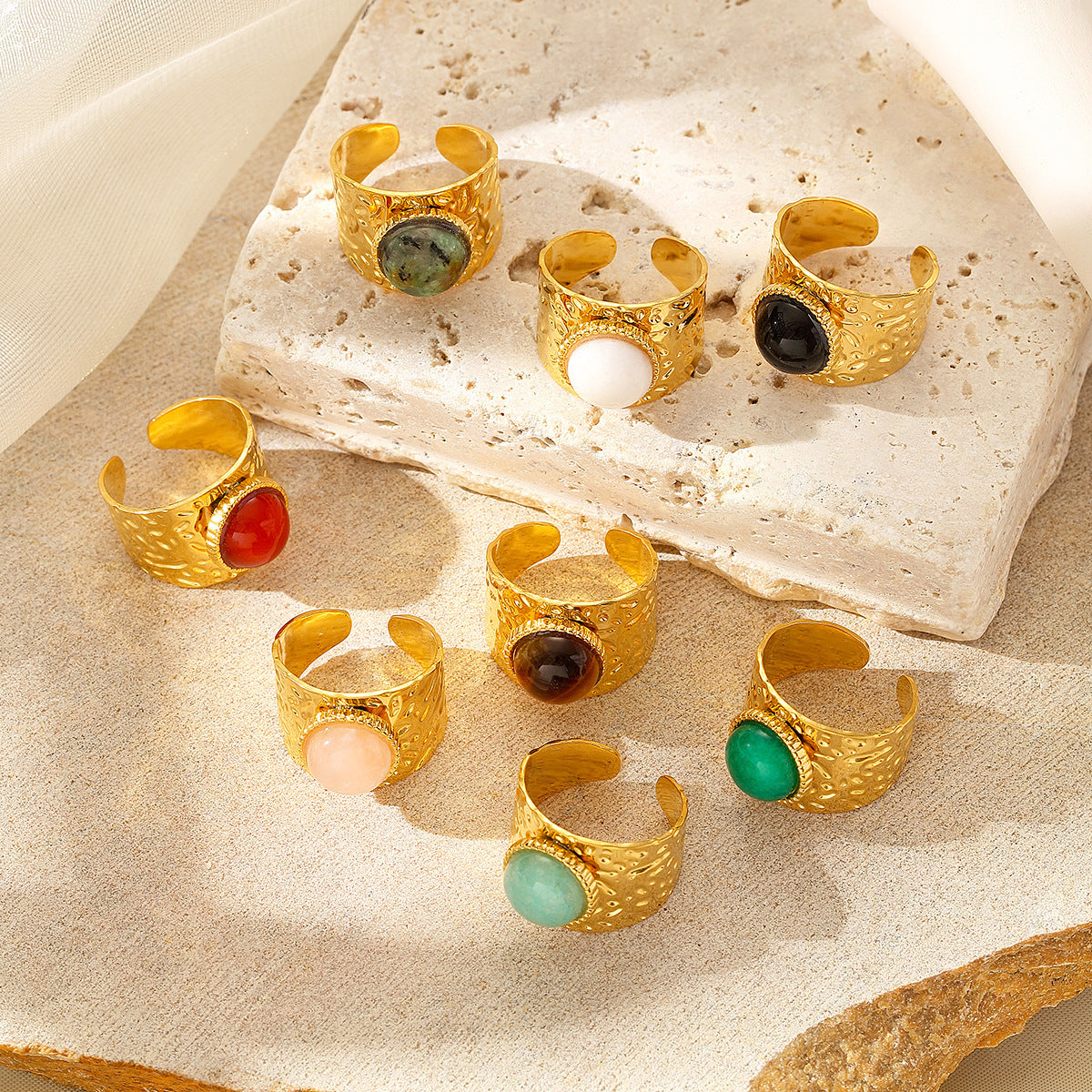 Gold rings with colorful gemstones on a textured surface