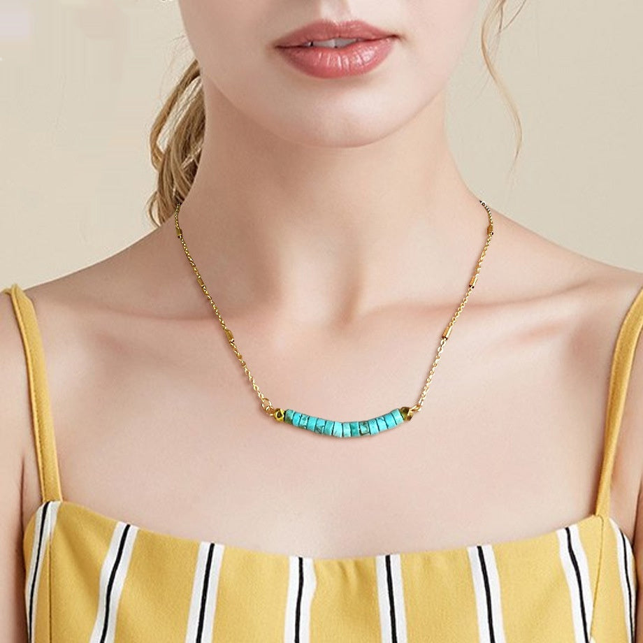 Necklace with turquoise beads worn by a person in a yellow dress.