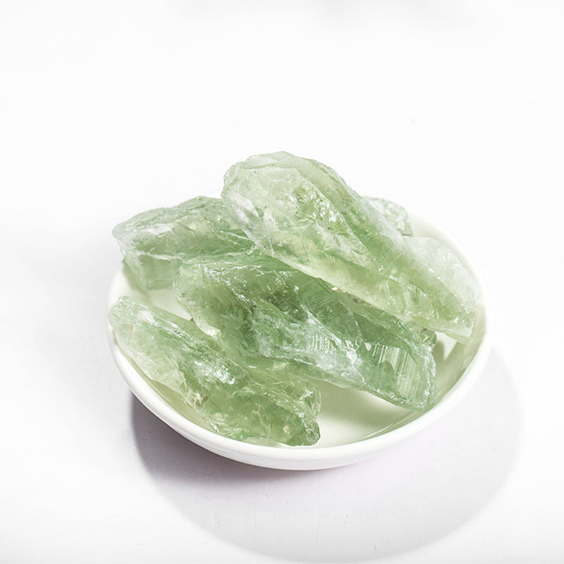 Green crystals in a white bowl on a white background