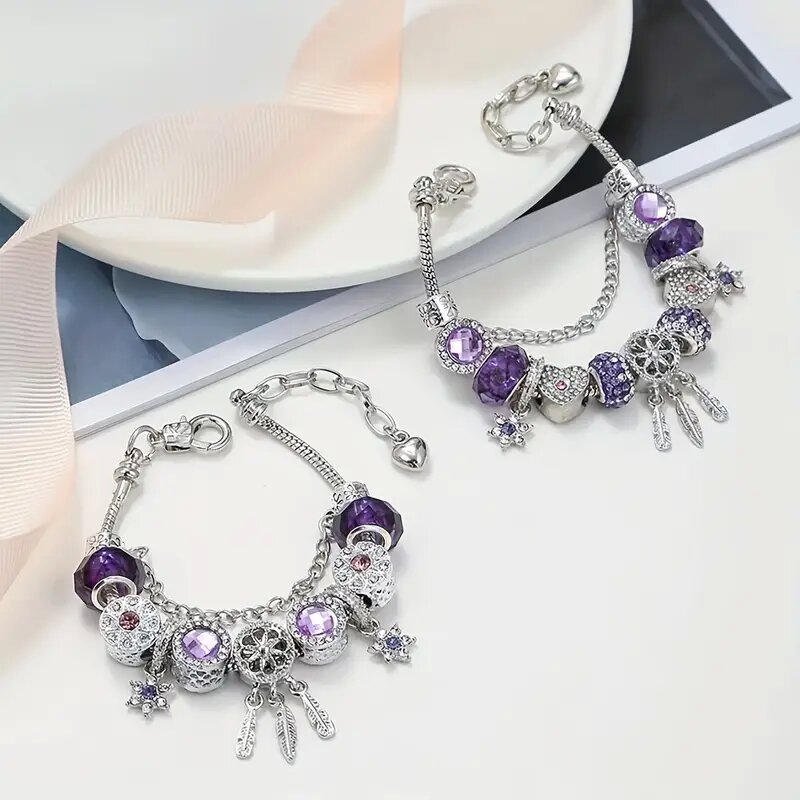 Silver bracelets with purple and clear gemstones on a white surface