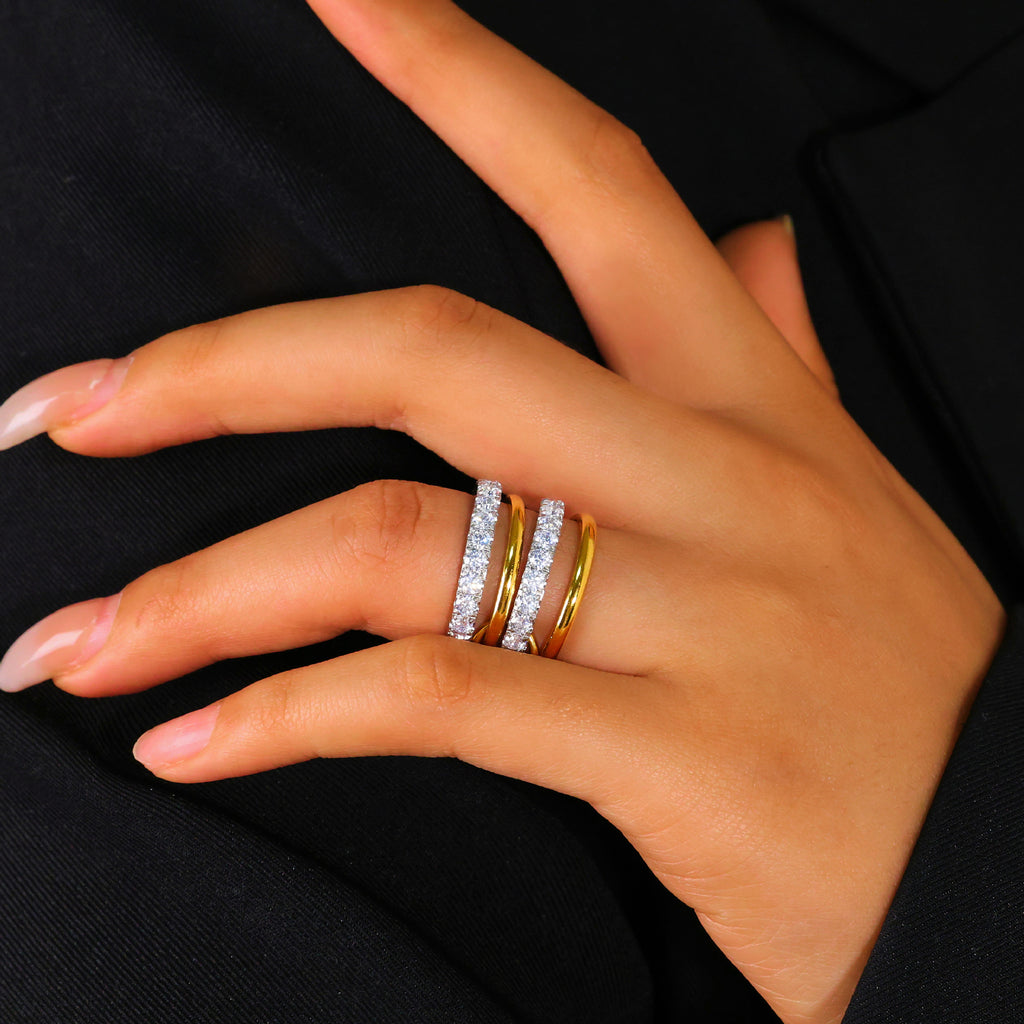 Hand wearing two gold rings on a black background