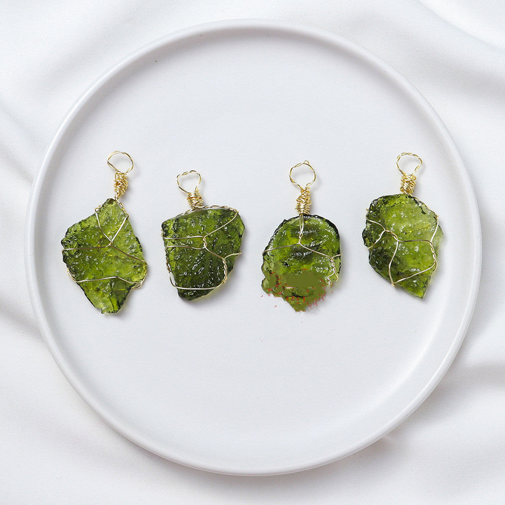 Four green stone pendants on gold wires displayed on a white plate.