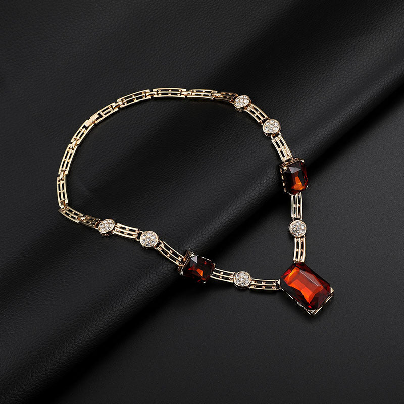 Gold bracelet with red and clear gemstones on a black fabric background