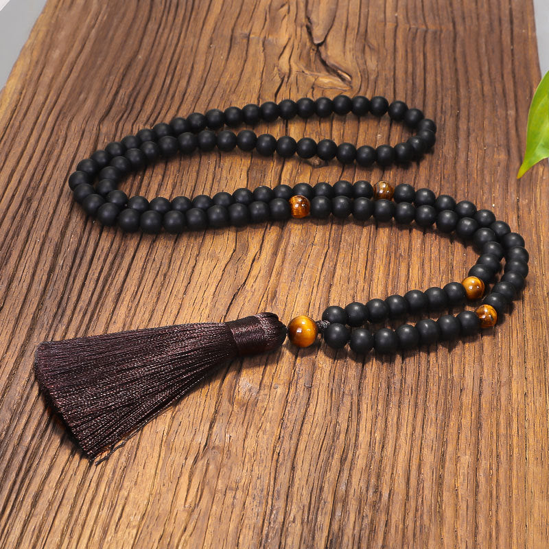 Black beaded necklace with a tassel on a wooden surface