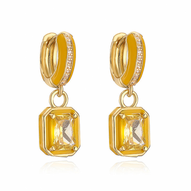 Gold hoop earrings with square citrine stones on a white background