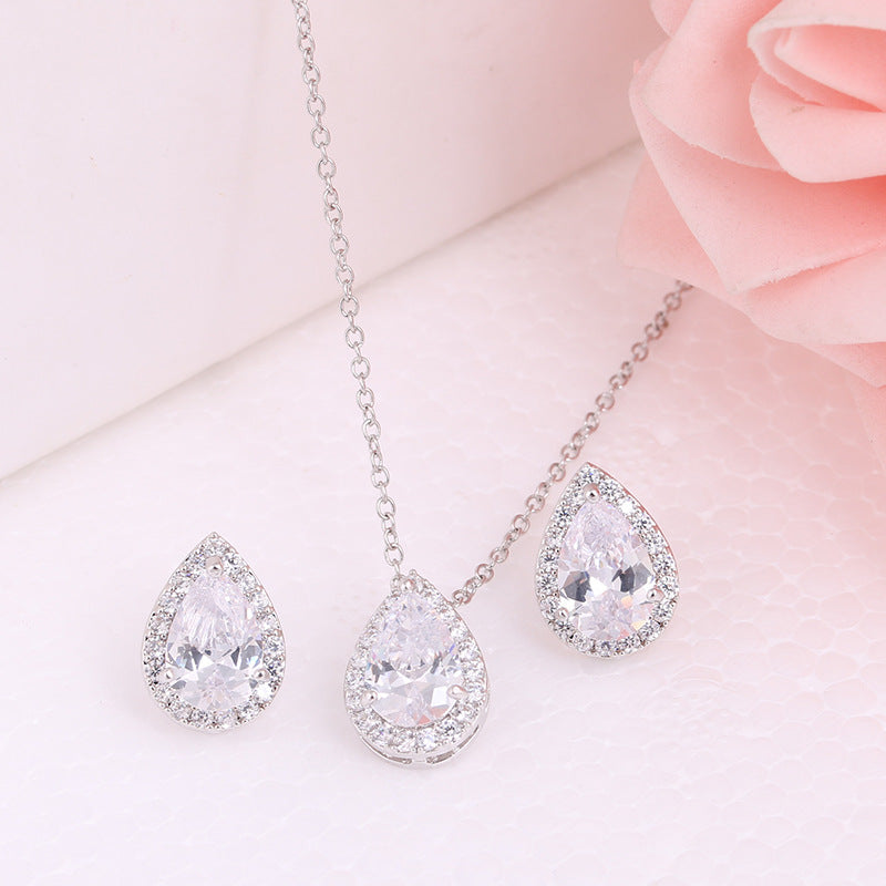 Teardrop-shaped jewelry set on a soft pink background