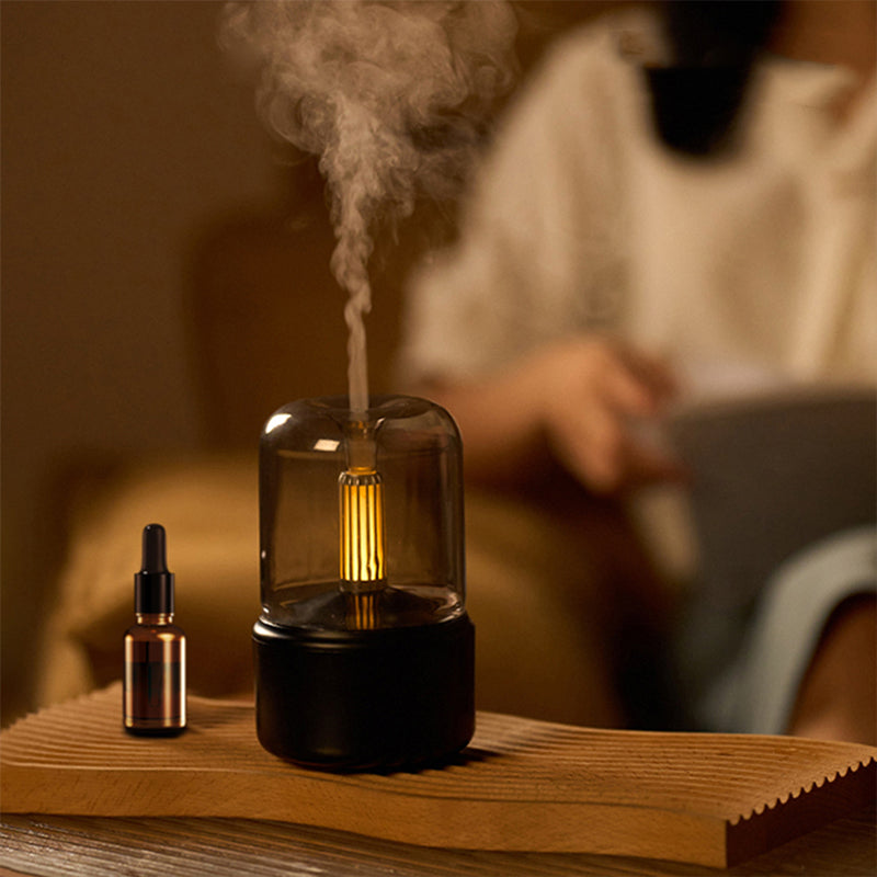 Smoking device with a lit bulb and dropper bottle on a wooden surface, with a blurred background of a person using a laptop.