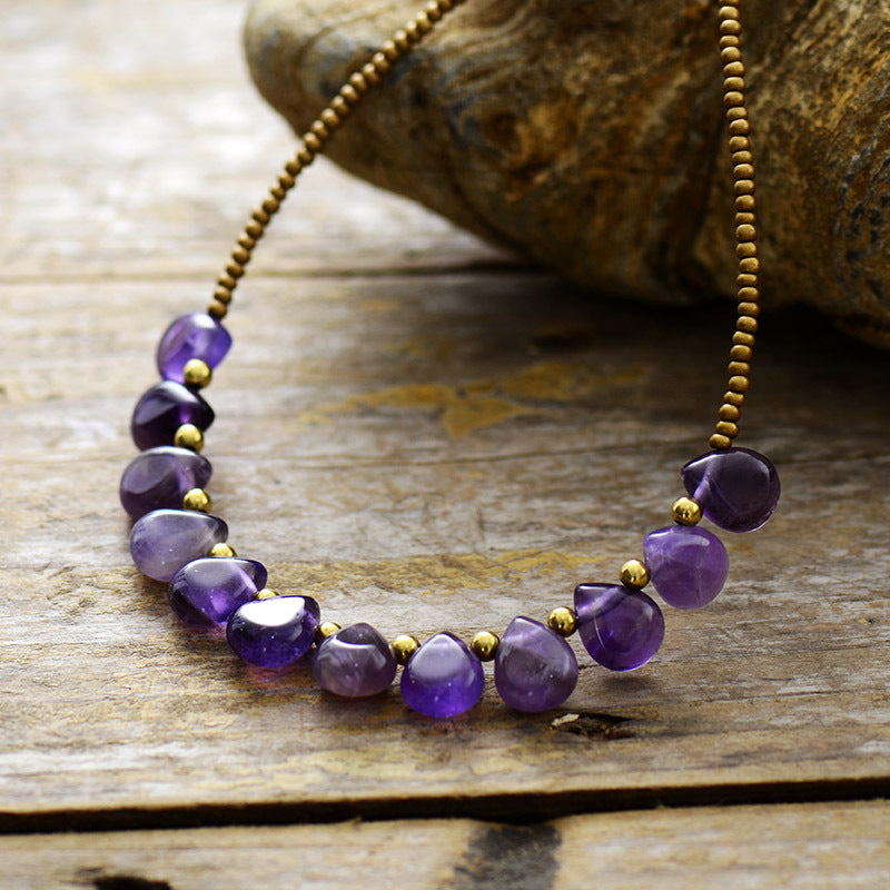 Necklace with purple beads and gold accents on a wooden surface