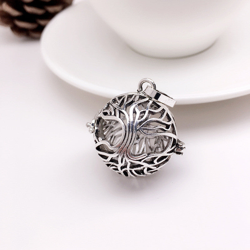 Silver tree-shaped pendant on a white surface with a blurred background