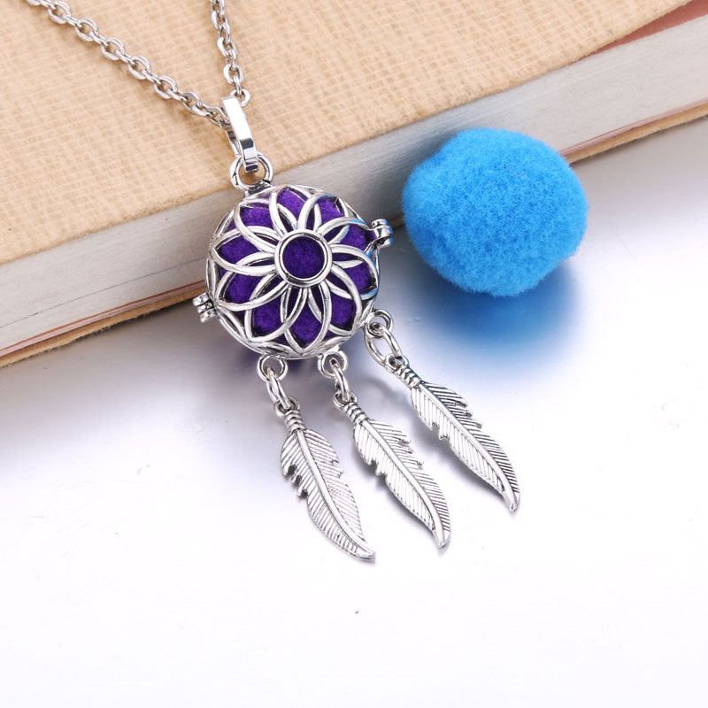 Necklace with purple circular pendant and feather charms on a white surface.