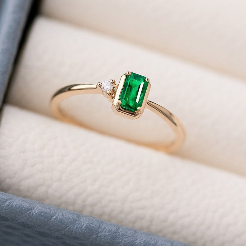 Gold ring with a green gemstone on a soft fabric background