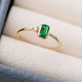 Gold ring with a green gemstone on a soft fabric background