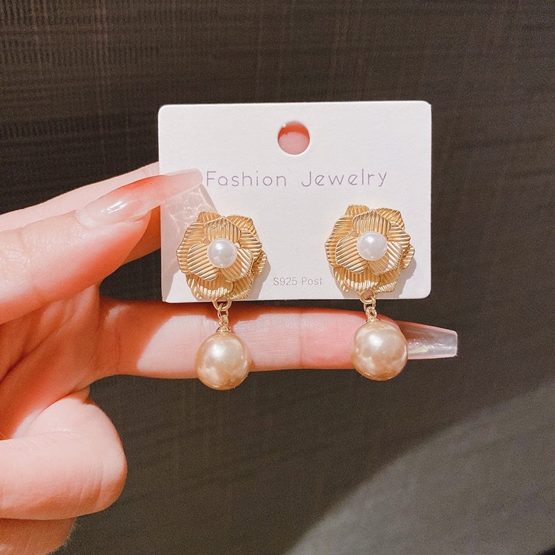 Gold earrings with pearl drops on a 'Fashion Jewelry' card held by a hand.