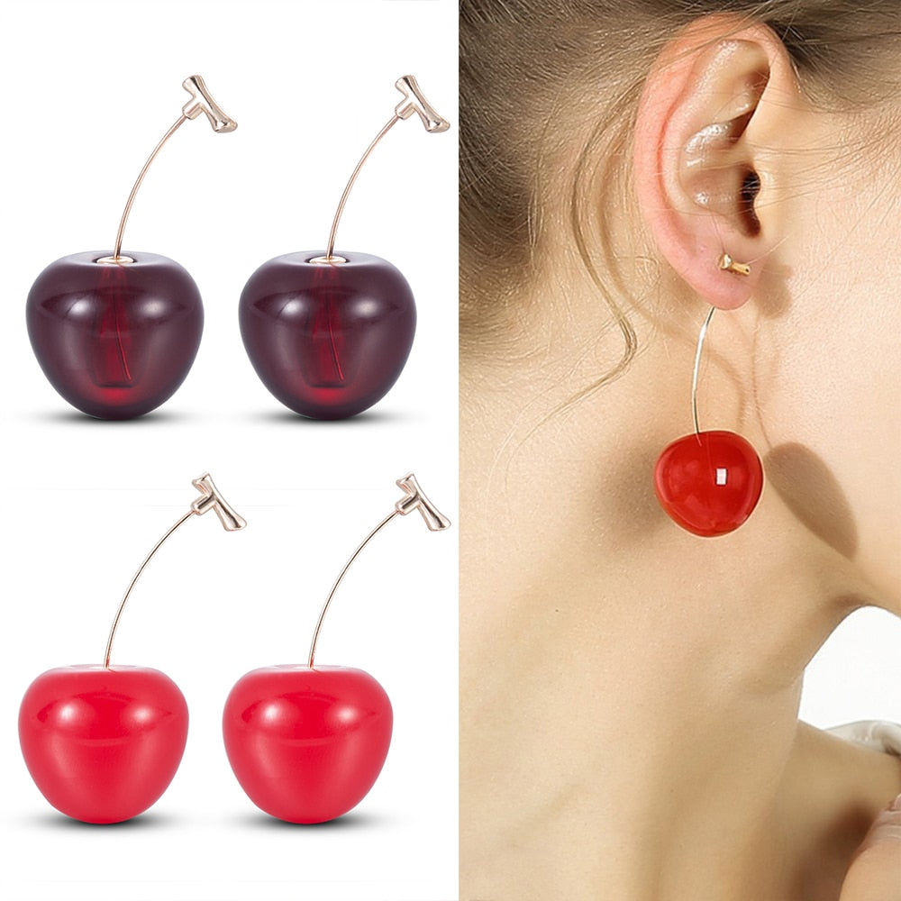 Cherry-shaped earrings on a white background with a close-up of an ear wearing one.