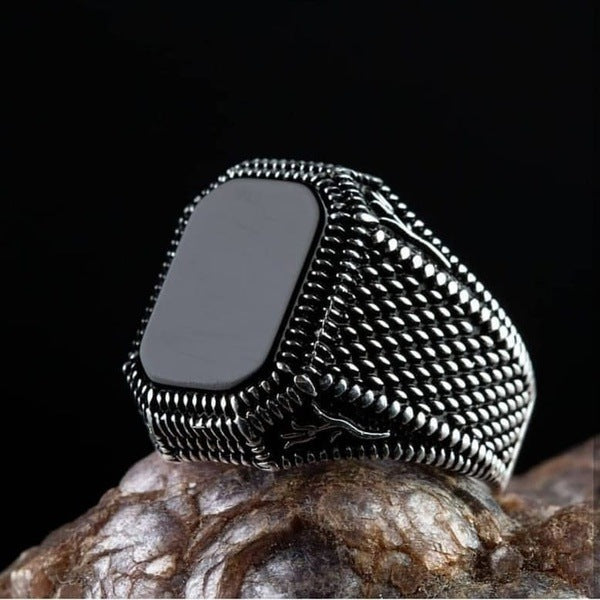 Silver ring with a black stone on a dark background