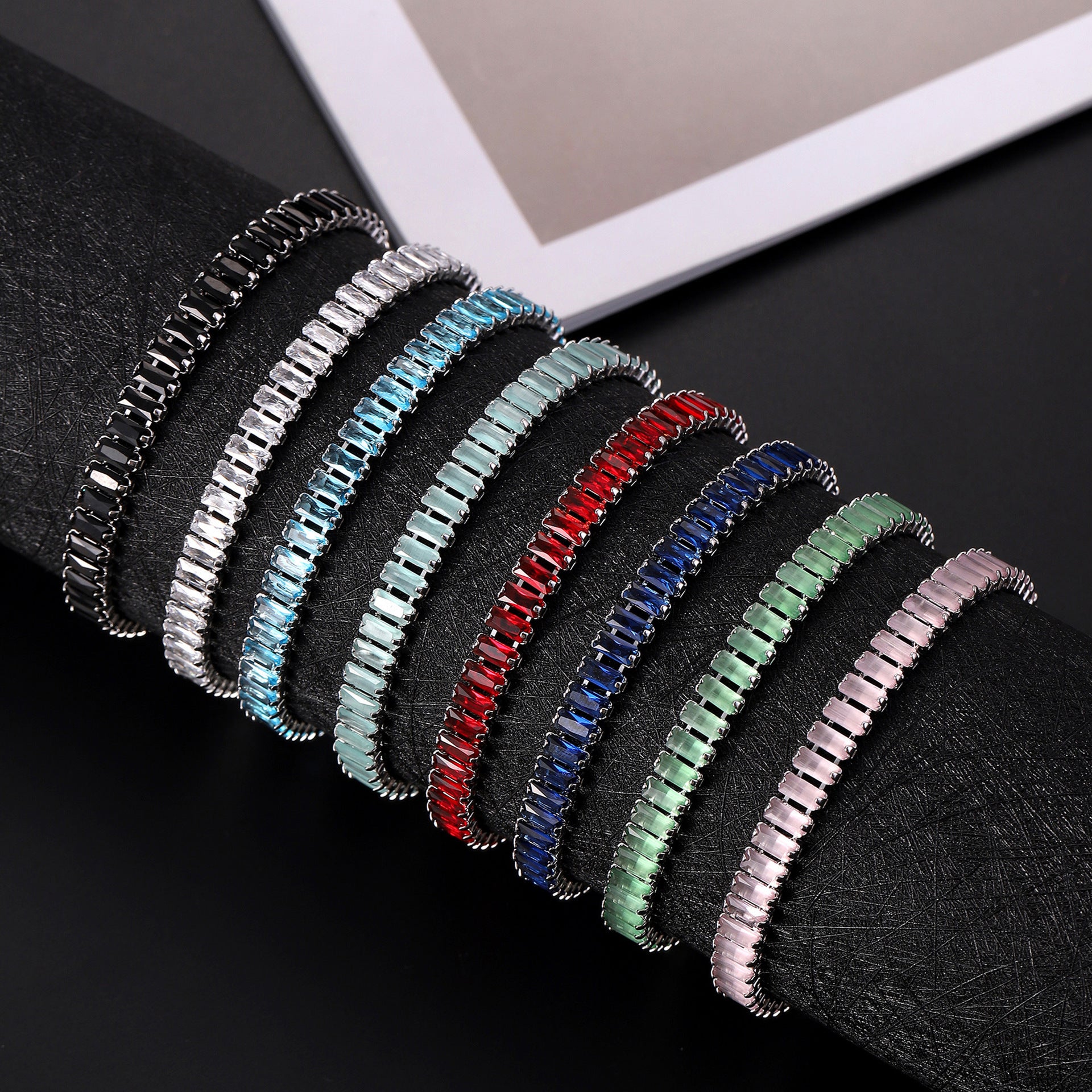Set of colorful bracelets on a black surface with a white frame in the background