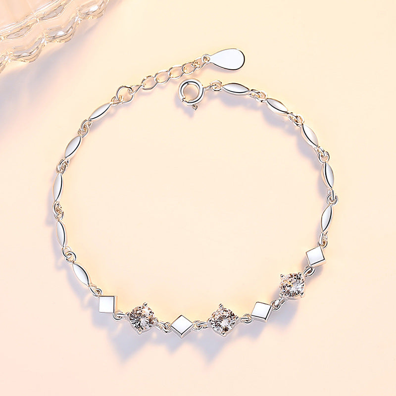 Silver bracelet with diamond-like stones on a light pink background