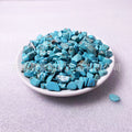 Turquoise stones on a white plate with a light gray background
