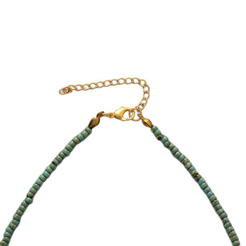 Necklace with green beads and gold clasp on a white background