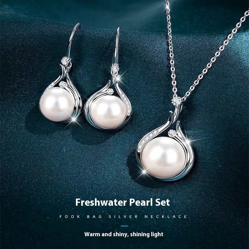 Pearl necklace and earrings set on a dark blue fabric background