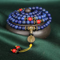 Blue beaded bracelet with gold, red, and black accents on a dark green background