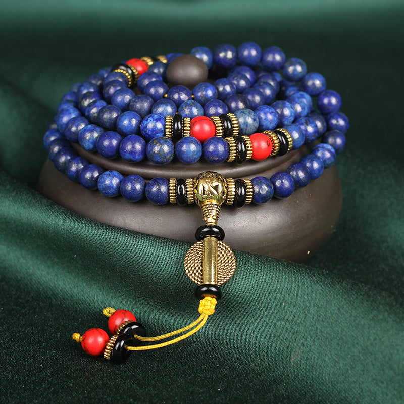 Blue beaded bracelet with gold, red, and black accents on a dark green background