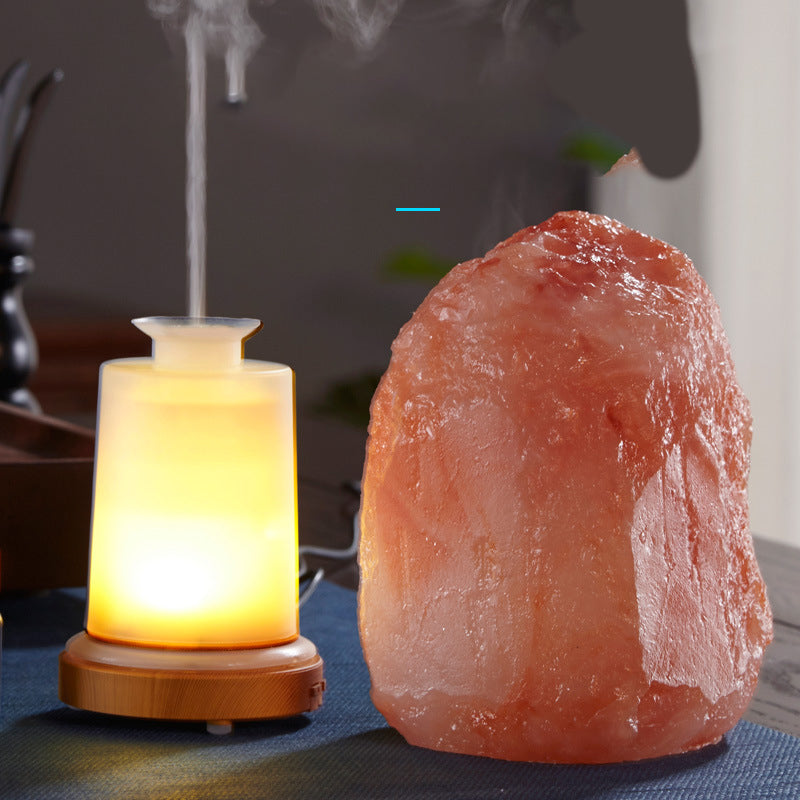 Himalayan salt lamp emitting steam next to a small light source on a dark surface.