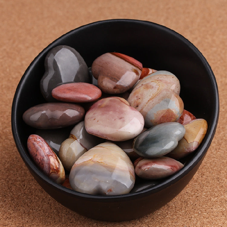 Black bowl filled with multicolored stones on a brown background