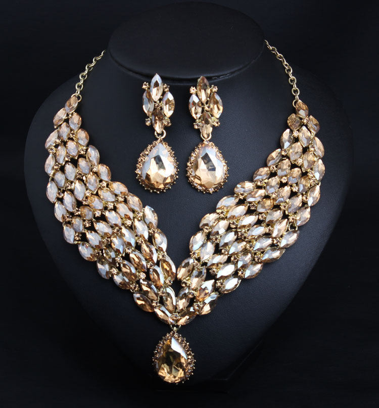 Gold and crystal necklace and earrings on a black background