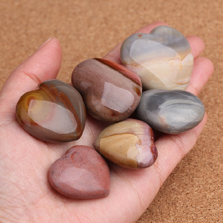 Hand holding a collection of polished agate stones with a brown background
