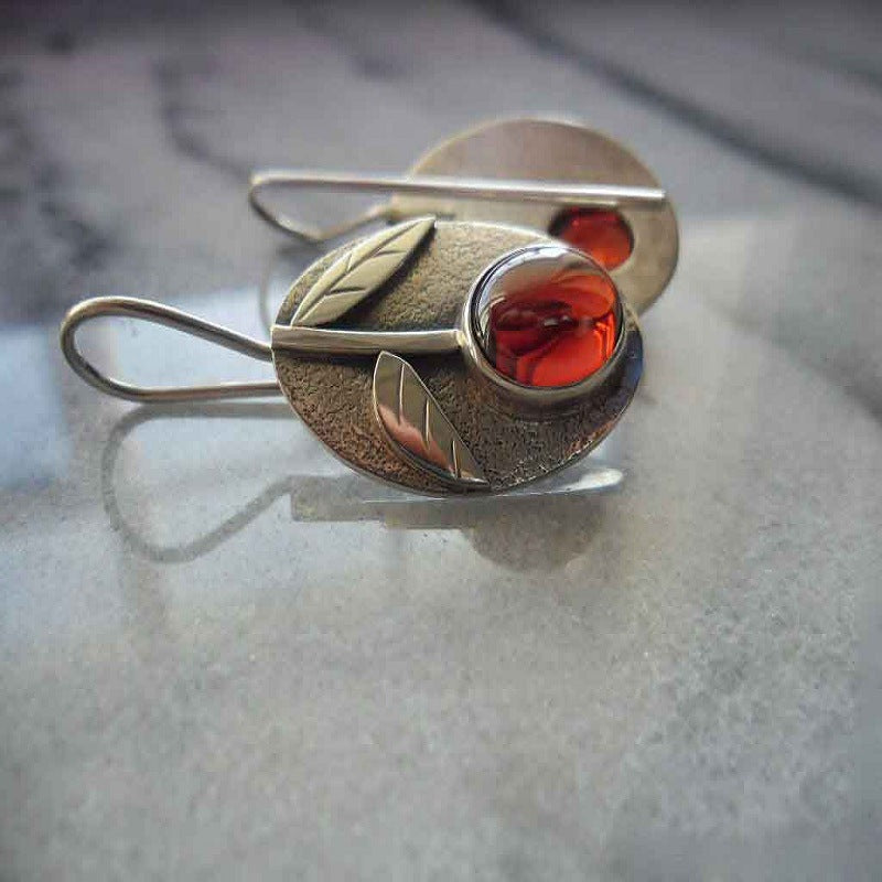 Silver brooch with red stone on a textured surface