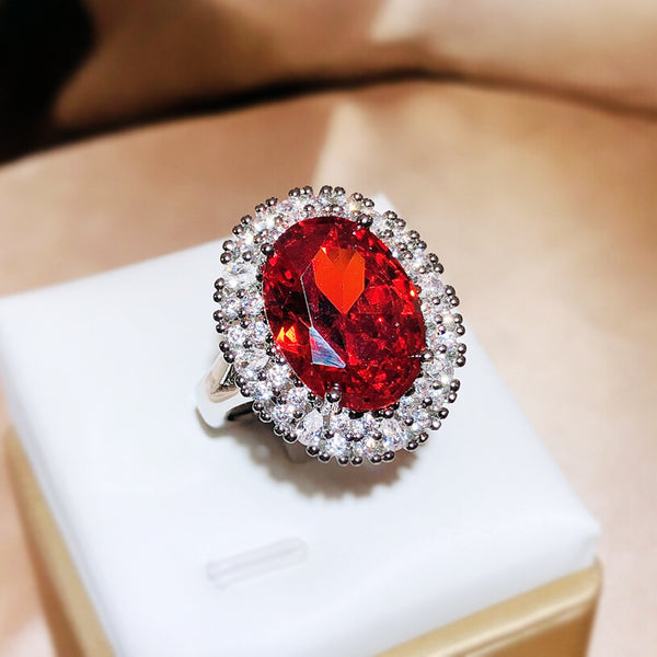 Ring with a red gemstone and silver accents on a white box
