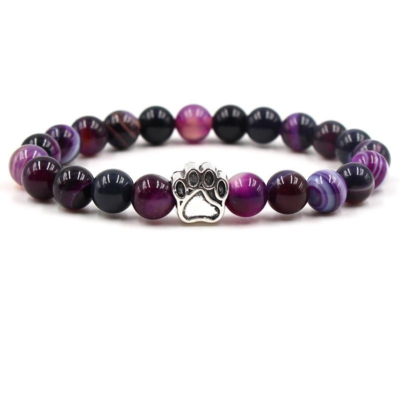 Purple and black beaded bracelet with a paw print charm on a white background