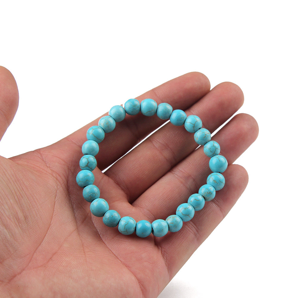 Turquoise beaded bracelet on a hand against a white background