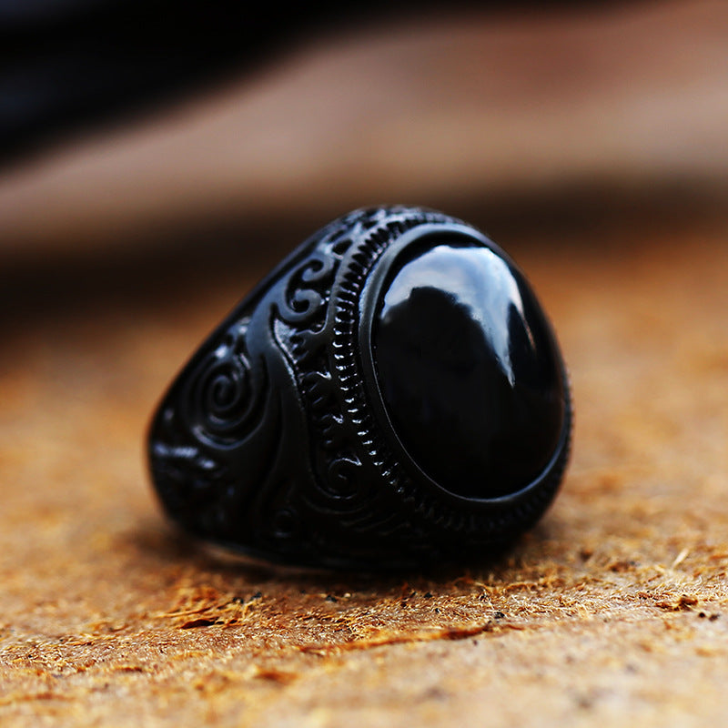 Black stone ring with intricate designs on a textured surface