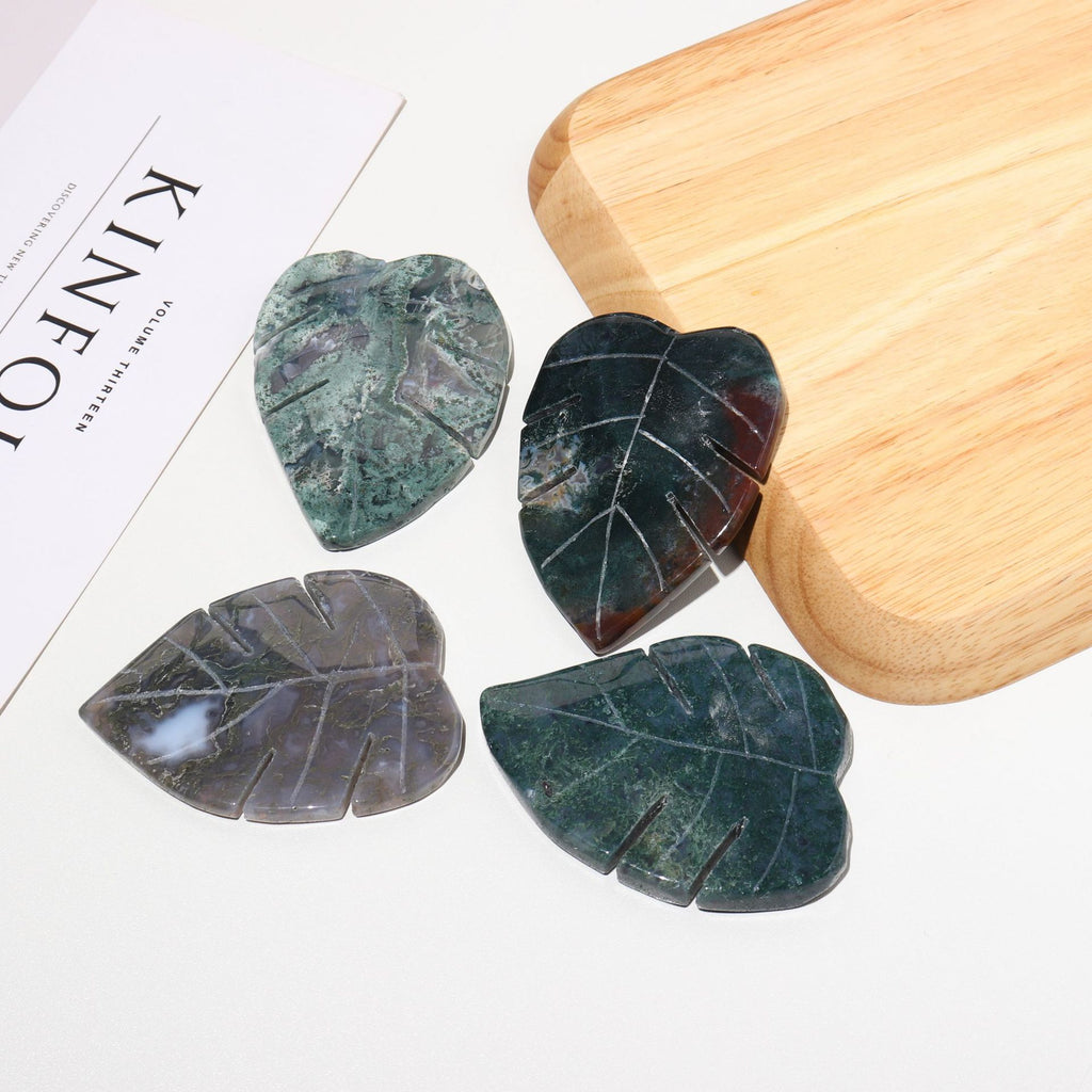 Four leaf-shaped stones on a wooden surface with a magazine in the background