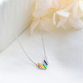 Necklace with a colorful pendant on a white surface with flowers in the background