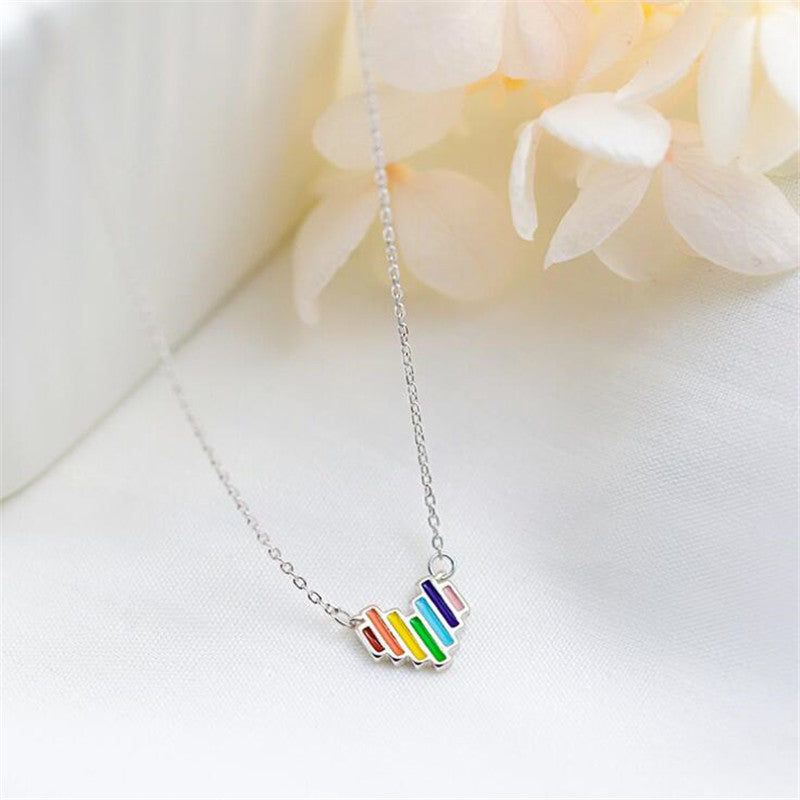 Necklace with a colorful pendant on a white surface with flowers in the background