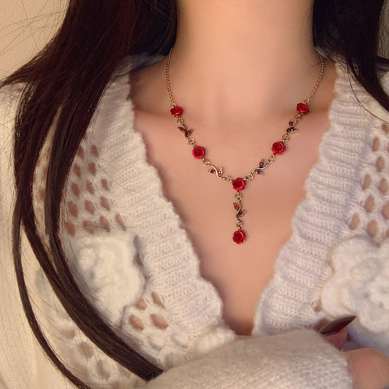 Necklace with red gemstones worn by a person in a white textured garment.