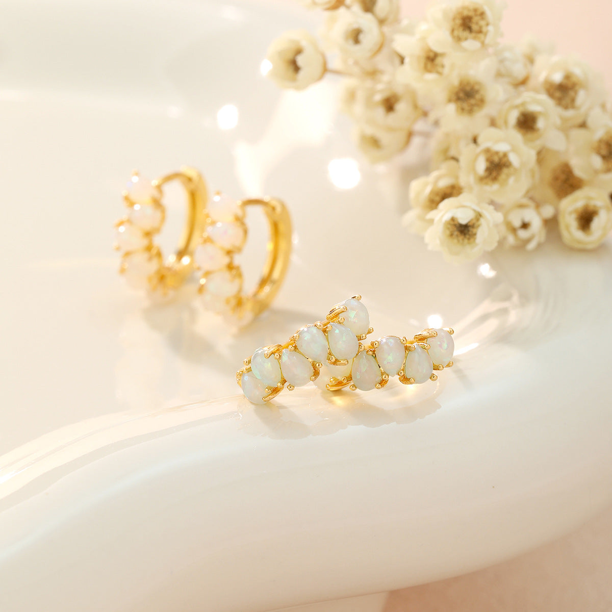 Gold and white opal jewelry set on a soft beige background with flowers.