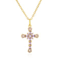 Gold cross necklace with pink gemstones on a white background