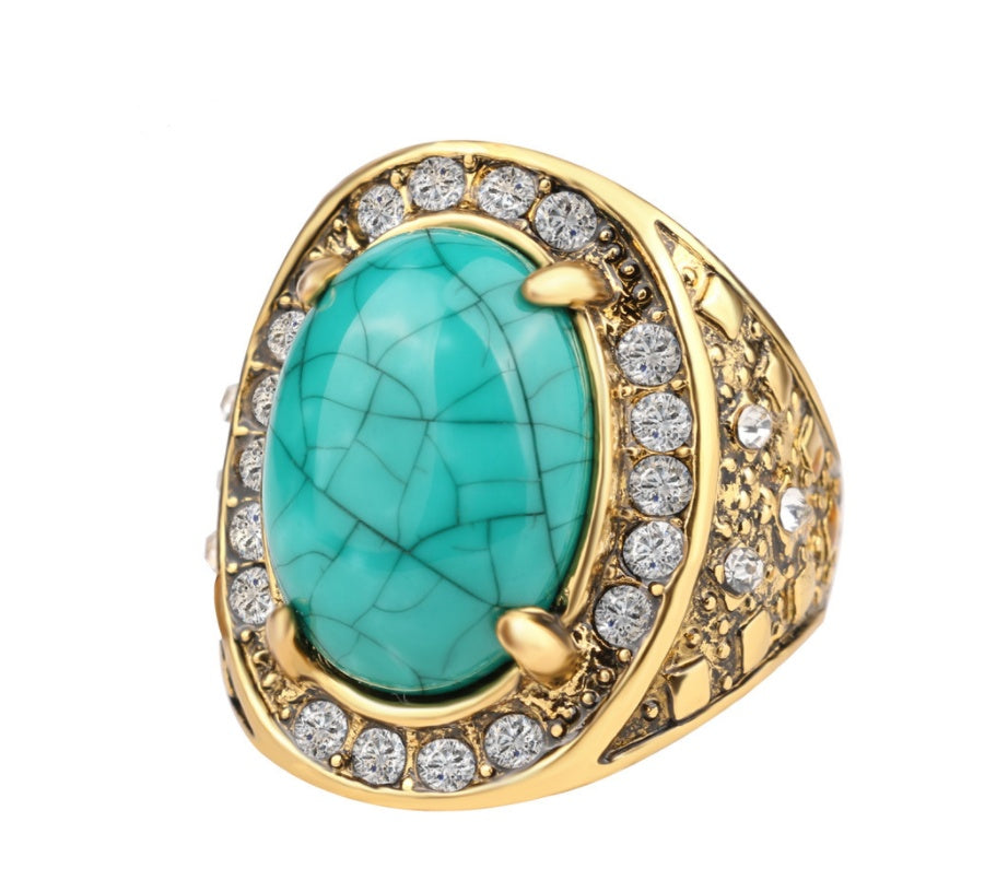 Gold ring with a turquoise stone and diamond accents on a white background