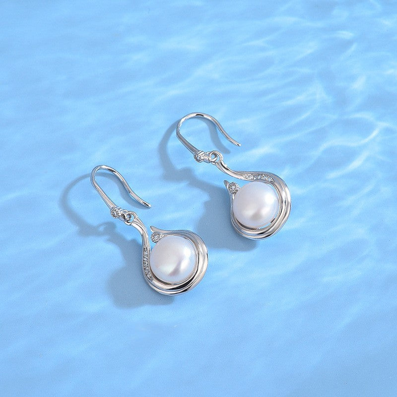 Pearl earrings with silver hooks on a blue water background