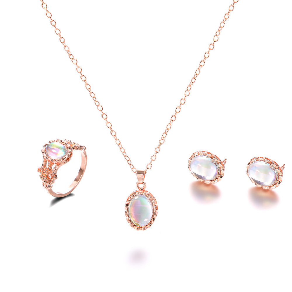 Rose gold jewelry set with necklace, ring, and earrings on a white background