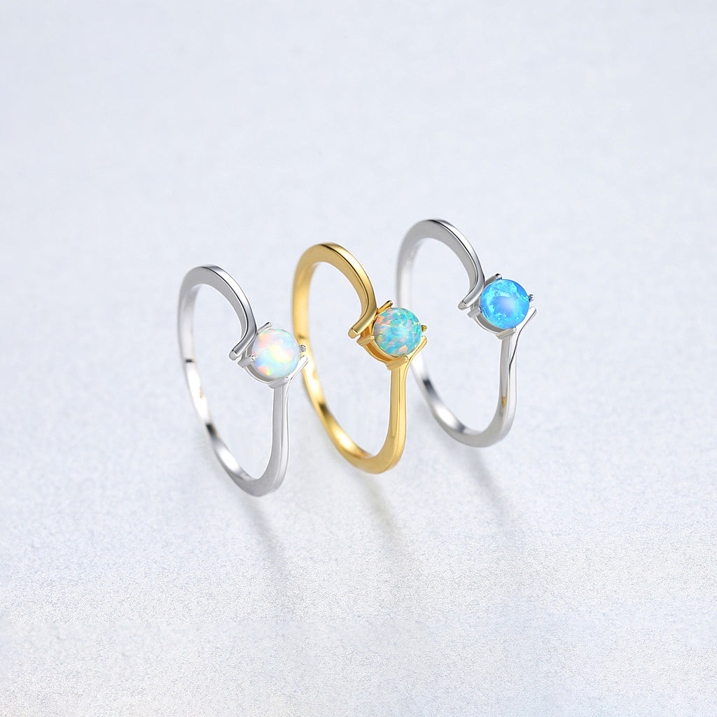 Three rings in gold and silver with blue gemstones on a light gray background