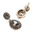 Pair of gold and black earrings on a white background