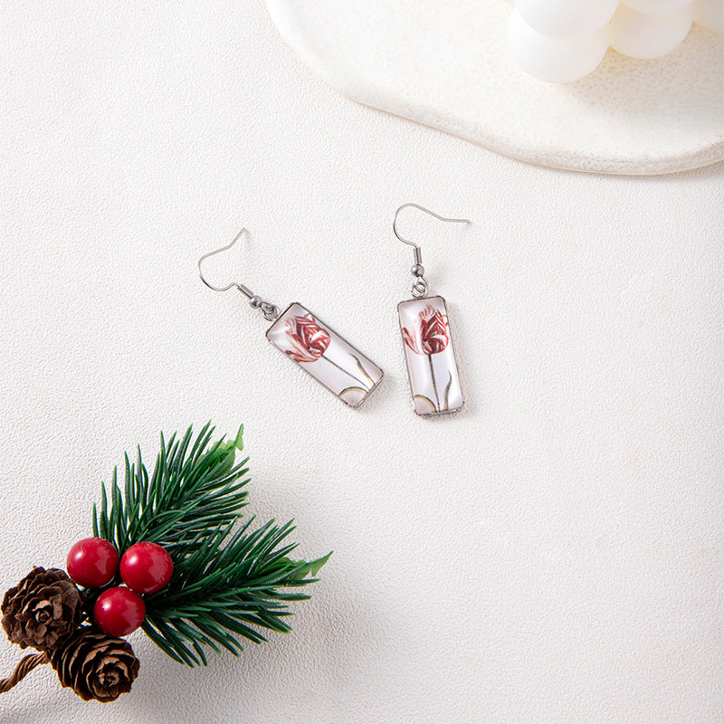 Pair of earrings with floral design on a white surface with decorative elements.